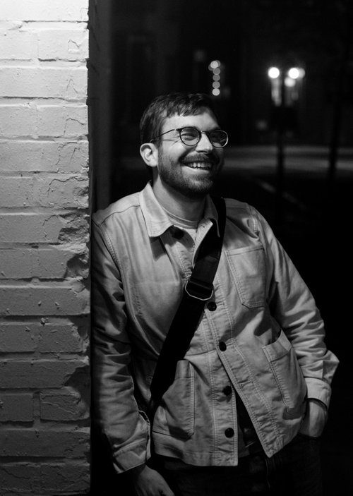 Jon Setter leaning against a brick wall at night